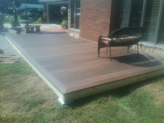 New wood deck and wicker chair beside a brick house in Greenwich